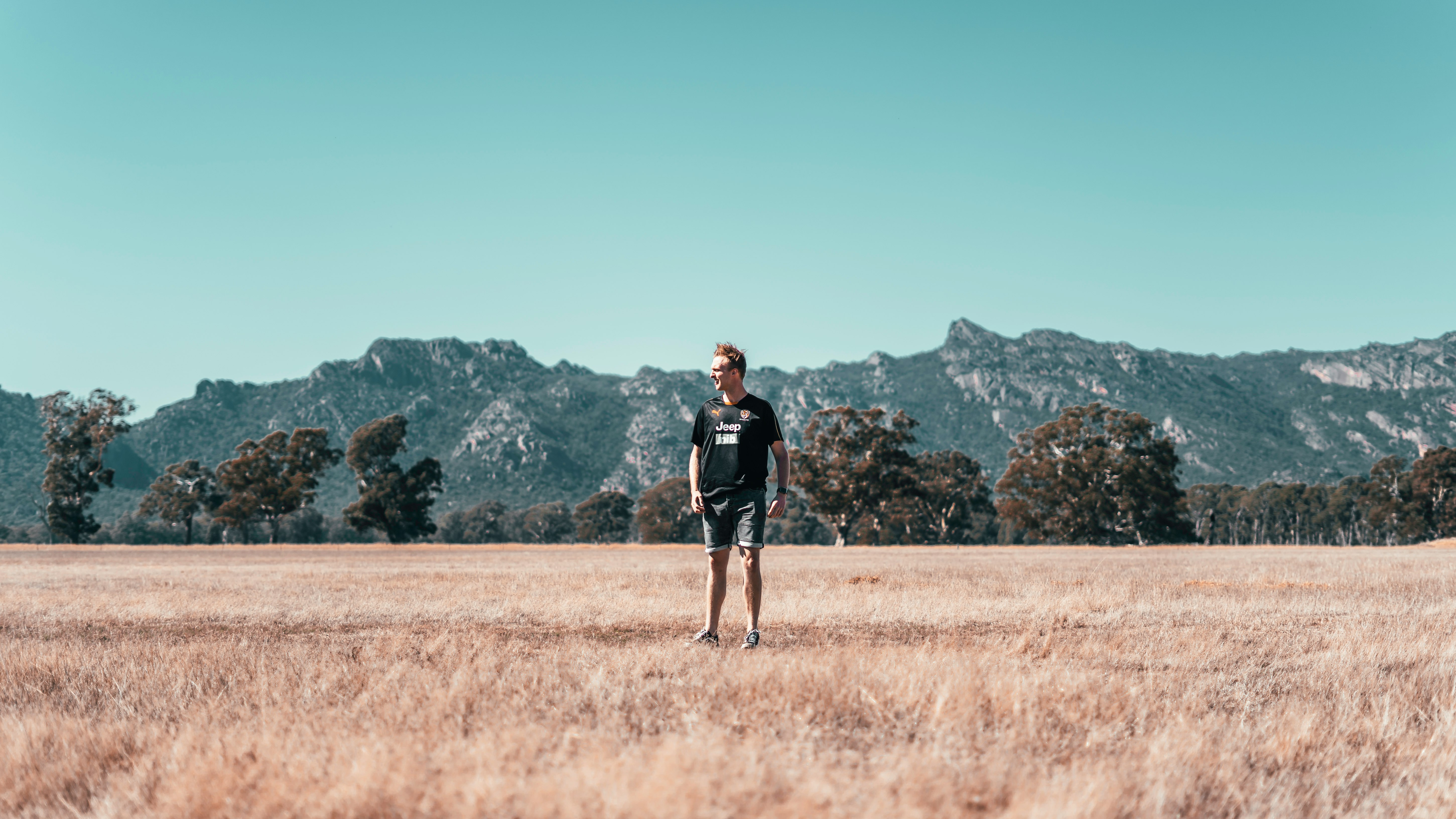 man in black jacket standing on brown grass field during daytime